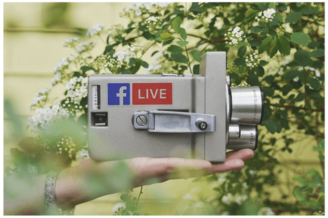 foto de una mano que sostiene una cámara de video con dos etiquetas relacionadas con facebook y la palabra LIVE