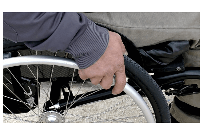 foto de una mano que gira una rueda de una silla de ruedas