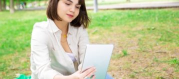 mujer leyendo una tablet en un parque