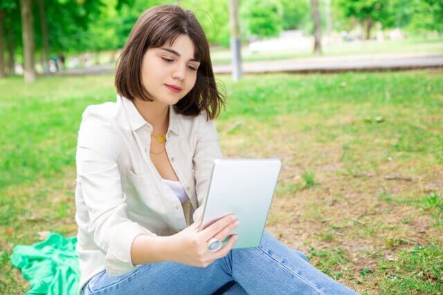 mujer leyendo una tablet en un parque