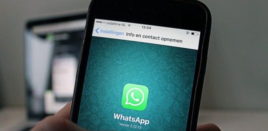 Persona con un smartphone en la mano y en la pantalla el logo de whatsapp