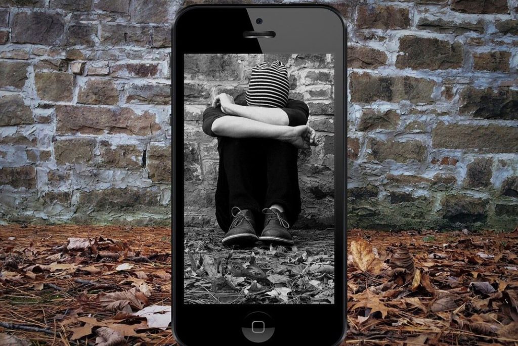 Imagen de un joven cubriendo su cara mostrada a través de un móvil