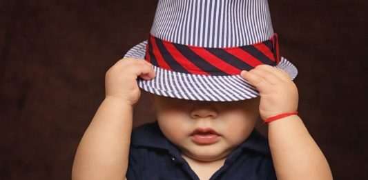 Bebé cubriendose la cara con un sombrero