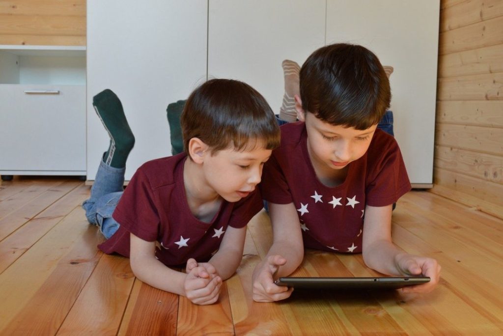 Niños acostados en el piso mirando una tablet